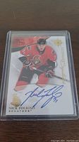 Front side of Nick Foligno hockey card showing him in red Ottawa Senators uniform and autograph in blue ink.
