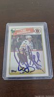 Front of the Ray Bourque Topps hockey card showing the player in uniform with autograph in blue ink.