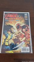 Photo of the Wolverine & Deadpool #44 comic book front cover in a protective plastic sleeve, artwork clearly visible showing both characters in aggressive postures.
