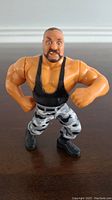 Front view of the WWF Hasbro Bushwacker Luke wrestling action figure showing muscular build, black singlet, camo pants, and black boots.