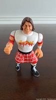 Front view of the figure showing facial expression, white shirt with Hot Rod logo, red kilt, and black boots.