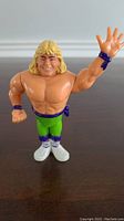 Front view of WWF Hasbro Shawn Michaels action figure wearing green pants and white boots, right arm raised.
