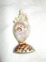 Sea shell cherry pic holder featuring an engraved fish image on front and spiny back detail made from smaller shells.