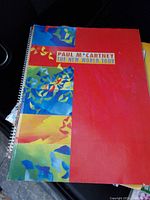 Spiral-bound book titled 'Paul M*Cartney The New World Tour' with a colorful cover showing art and text.