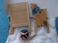 Photo showing two miniature wooden washboards, one plain and one decorated with blue ribbons and painted hearts, a small pink jam jar with green lid and bow, and a wooden dowel stirring stick.