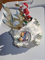 Top and side view of musical Christmas decoration showing Santa on glittery ice castle with skating children below