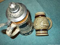 Top view of German musical beer stein with detailed silver lid and beige handle shaped like a figure.