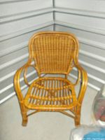 Front view of vintage wicker arm chair showing woven backrest, seat, and curved armrests in natural brown color.