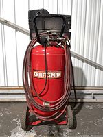 Front view showing Craftsman air compressor red tank with wrapped hose and black motor housing.
