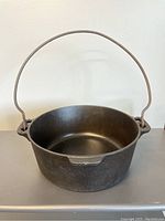 Front angled view of restored and seasoned large block Griswold cast iron Dutch oven, showing smooth interior and bail handle.