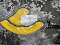 Photo of steering wheel lock with yellow padded wheel cover inside a clear plastic bag on a rough concrete floor.