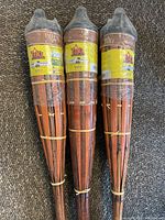 Three new bamboo Tiki torches laid side by side on carpet, showing caps and labels.