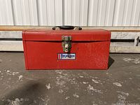 Red metal tool box with All American label and latch