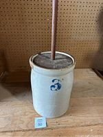 Full view of the stoneware butter churn with wooden dasher handle inserted, showing number 3 on the front.