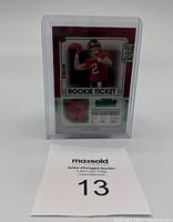 Photo of Kyle Trask football rookie card with a pink patch, encased in plastic holder, displayed front facing.