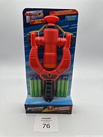 Front view of the Adventure Force red slingshot dart blaster in packaging, showing included foam darts and pull-back firing mechanism.