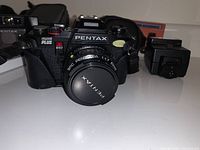 Pentax Program Plus camera with SMC Pentax-A 50mm lens and lens cap, AF200T flash to side