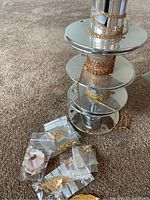 Four metal spools each wound with chains and several small plastic bags with clasps and accessories on carpeted floor.