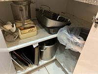 Overview of kitchen items including food processor, roasting pans, bakeware, and stock pot arranged on shelving.