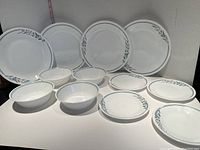 Set of 4 dinner plates, 4 bread and butter plates, and 4 bowls with Corelle Rosemarie green leaf and pink tulip design on white.