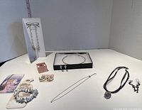 Full view of all jewelry items including necklaces, earrings, rings, bracelets and promotional pieces arranged on a flat surface.