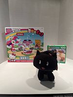 Front view of Hello Kitty Mega Bloks 223 piece set box, Pezzi Giochi 100 puzzle box, and black Scatty Catty plush toy with tags