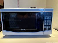 Front view of the RCA microwave, showing the black front with control panel and buttons on the right side.