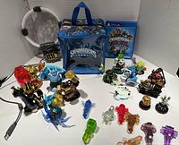 Full lot showing the Skylanders PS4 game, white Traptanium Portal, multiple Skylanders figures, assorted trap crystals, and two carrying cases.