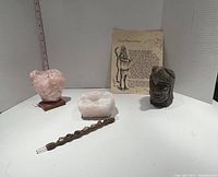 Overview photo of all five items: rose quartz heart crystal on wooden base, white quartz tea light holder, handcrafted eagle-headed Native American sculpture, leather wrapped gem wand, and Sioux Chief prayer print.