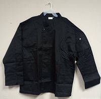 Front view of one black Chef Works chef jacket showing long sleeves, mandarin collar, and snap button closure.