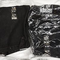Folded black jean shorts with size W34 tags and W40 packaged shorts in plastic with visible Silver Jungle & Co. branding.