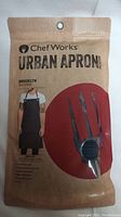 Front of sealed Chef Works Urban Apron Brooklyn Bib Apron package showing product image and branding.