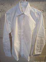 White dress shirt with long sleeves, standard collar, and buttoned cuffs visible from the front.