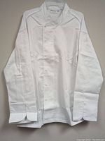 Front view of white chef jacket showing the double-breasted snap button closures and Mandarin collar.