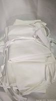 Folded white aprons with ties visible, stacked in factory packaging.