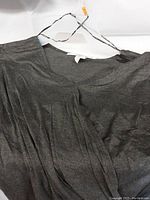 Close-up of the grey fabric detail and neckline of the women's shirt on a hanger.