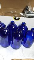 Blue glass bottles grouped inside box showing shape and color