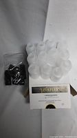 Photo shows several translucent 2 oz squeeze bottles partially arranged inside a white Vaplex box, with a ziplock bag of black plastic caps to the side.