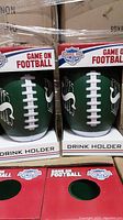 Two green football-shaped drink holders side by side in red 'Game On Football' packaging box