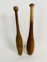 Front view of two antique wooden bowling pins showing their height and shape