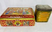 Photo of large German biscuit tin with medieval art and antique golden Dale-Ton Tea tin side by side