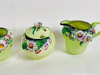 Close side view of the three-piece Carlton Ware set showing floral relief decoration.