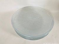 Stacked view of clear Sasaki glass plates with rain pattern showing textured design and smooth edges.