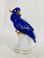 Front right profile of parrot figurine on pedestal