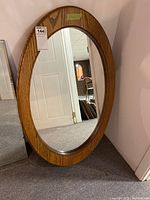 Front angle view of oval wooden framed mirror showing its size and shape.