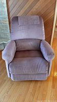Front view of a purple fabric LaZBoy reclining chair with arm and head covers on hardwood floor.