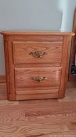 Front view of one Shermag wooden night table with two drawers and brass handles.