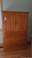 Front view showing two upper doors and three drawers with metal handles.