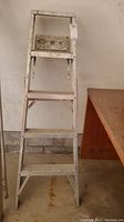 Full view of an aluminum 4 step painter's ladder showing overall condition and paint marks.