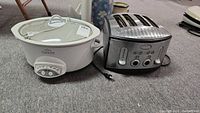 Photo showing the Rival Crock Pot slow cooker and Farberware 4-slice toaster side by side on carpeted floor.